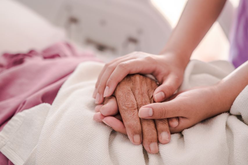 Zwei junge Hände halten eine alte Hand.