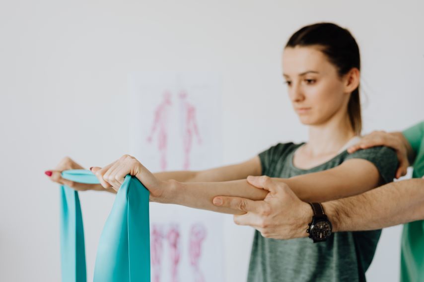 Eine junge Frau mit einem Trainingsgerät bei der Physiotherapie.