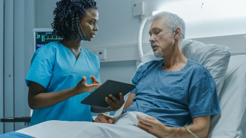 Eine Ärztin spricht mit einem Patienten im Bett.