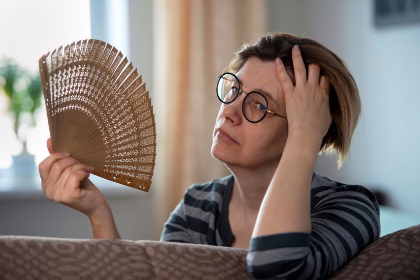Eien Frau fächelt sich mit einem Fächer Luft zu.