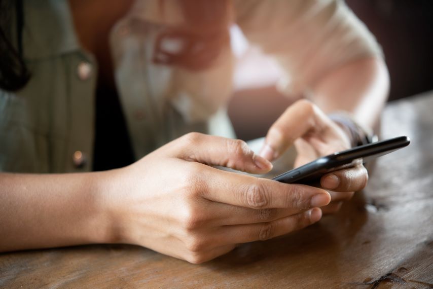 Eine Frau sitzt an einem Tisch, eine jüngere Frau reicht ihr ein Glas.