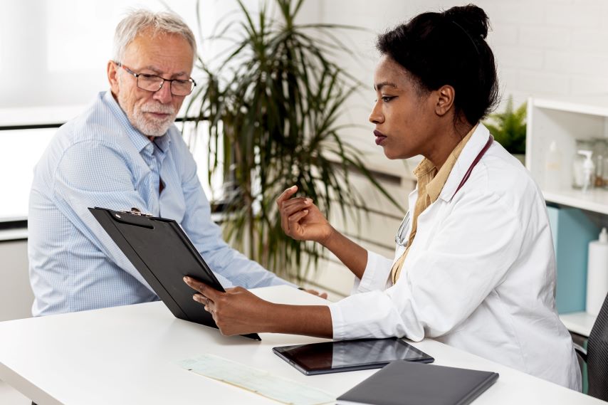 Eine Ärztin erklärt einem älteren Patienten etwas.